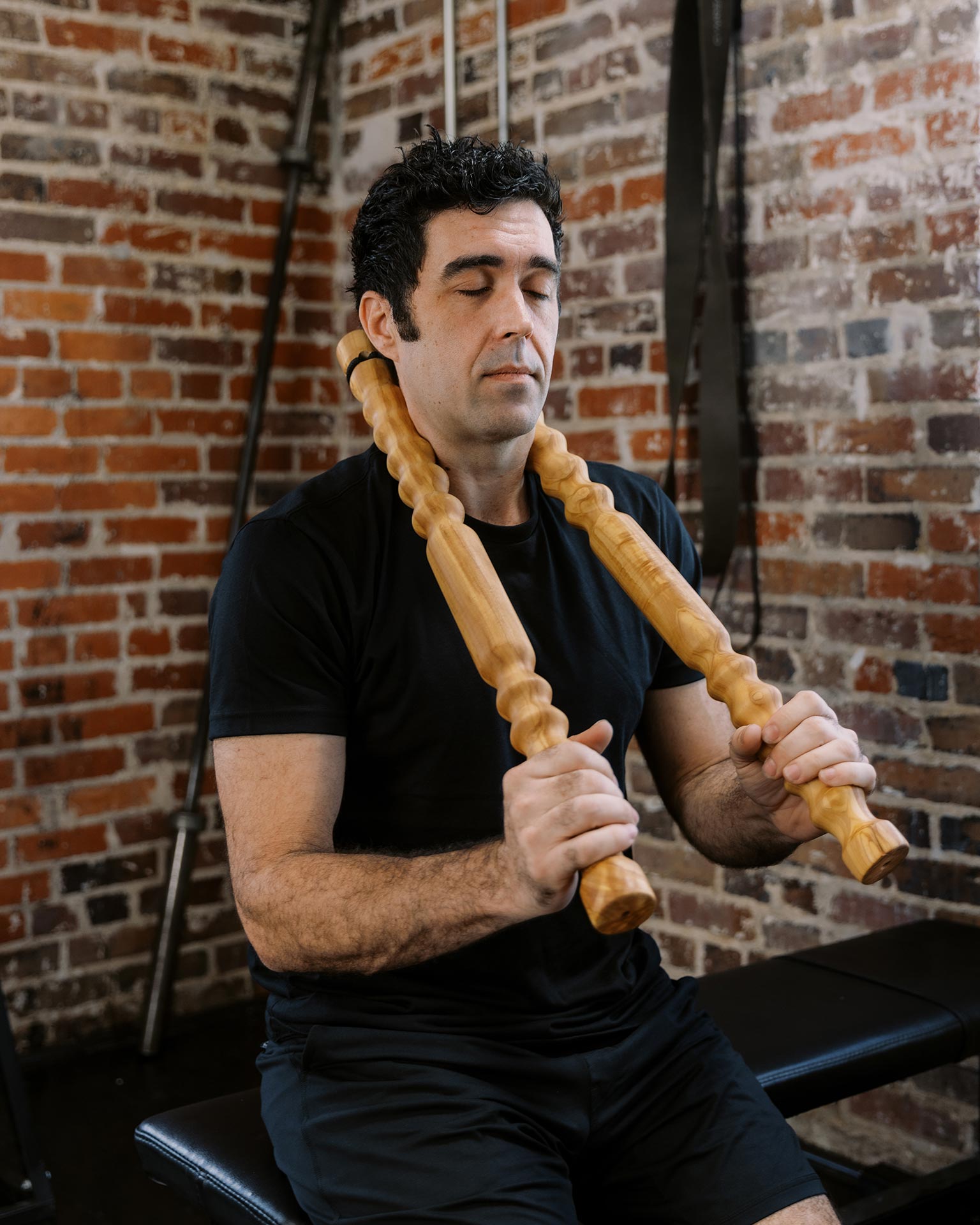 Man using wooden muscle therapy sticks