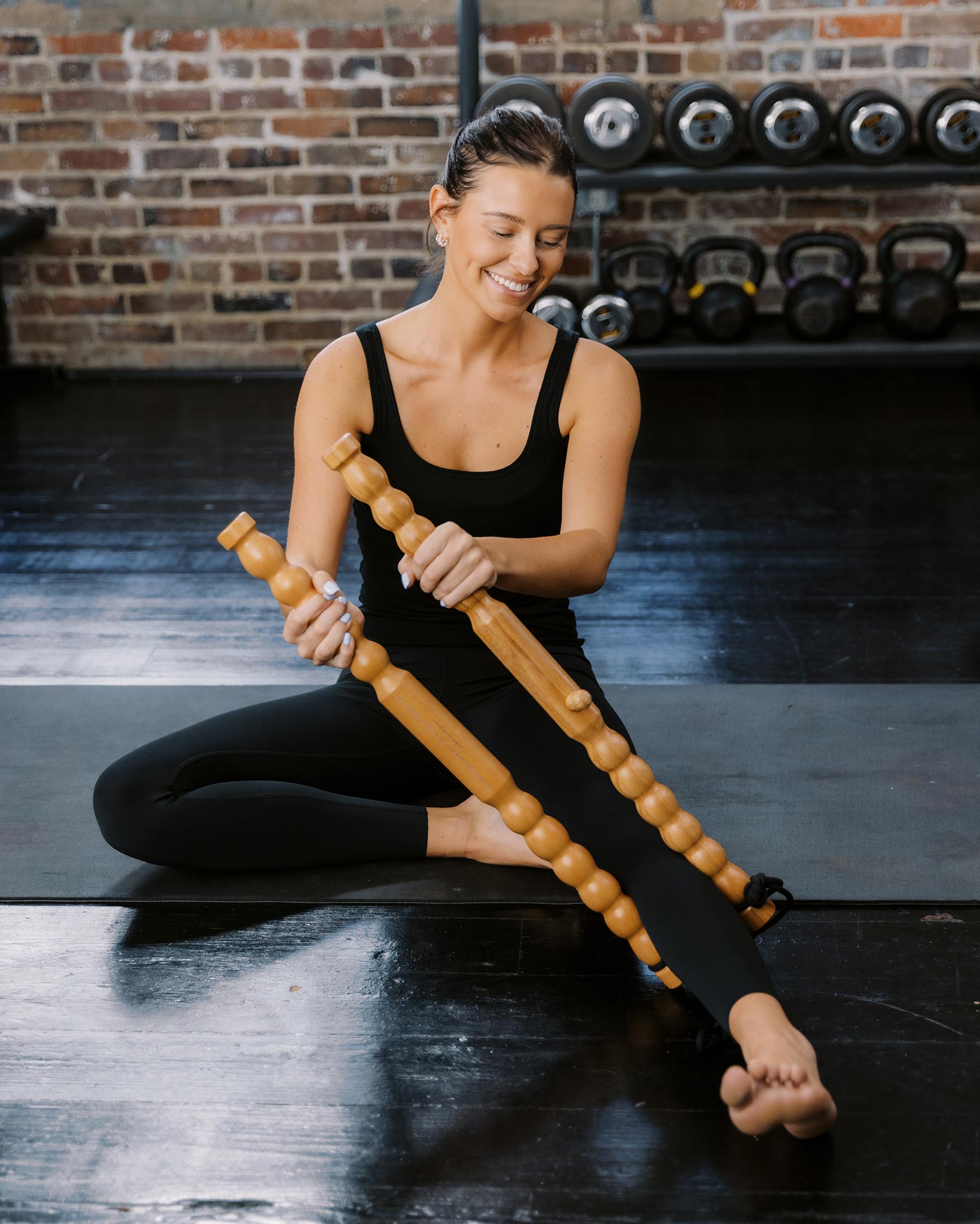 Woman using a wooden massage sticks in a gym setting
