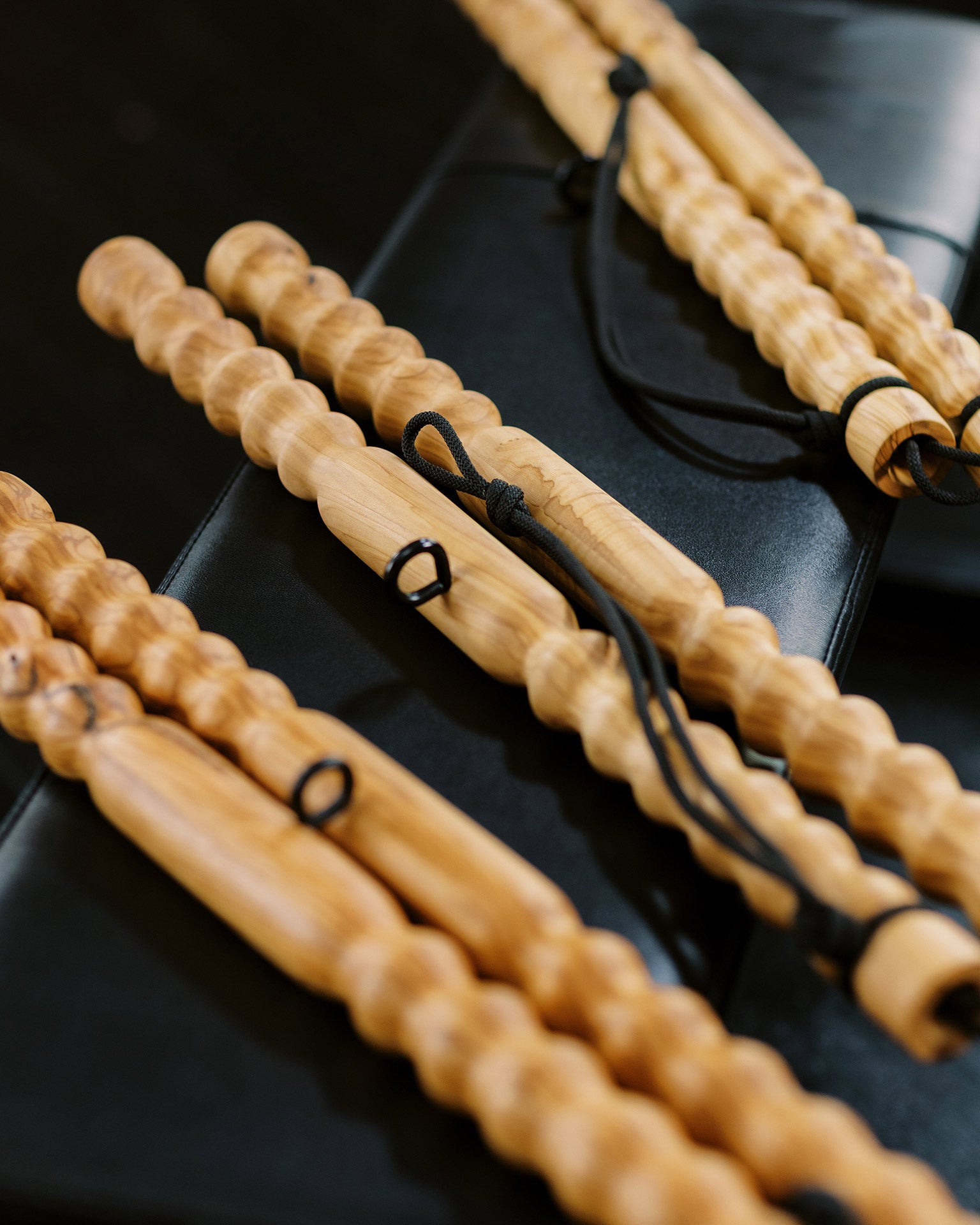 Three wooden muscle massage tools laying on a black workout bench