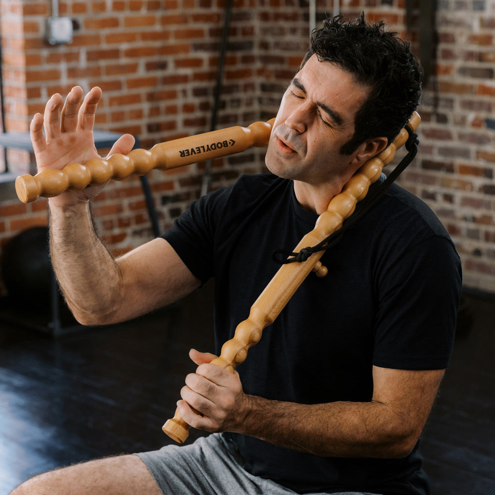 Man using wooden muscle massage sticks on his neck.