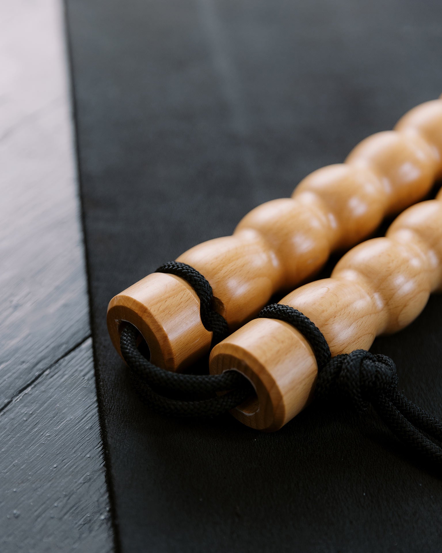 Wooden Body Lever massage tool sitting on a black workout mat.