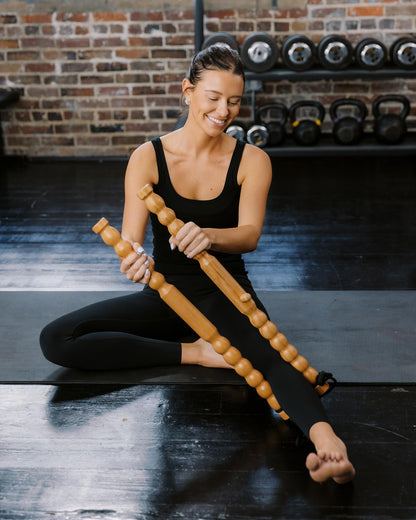Woman using a wooden massage sticks in a gym setting