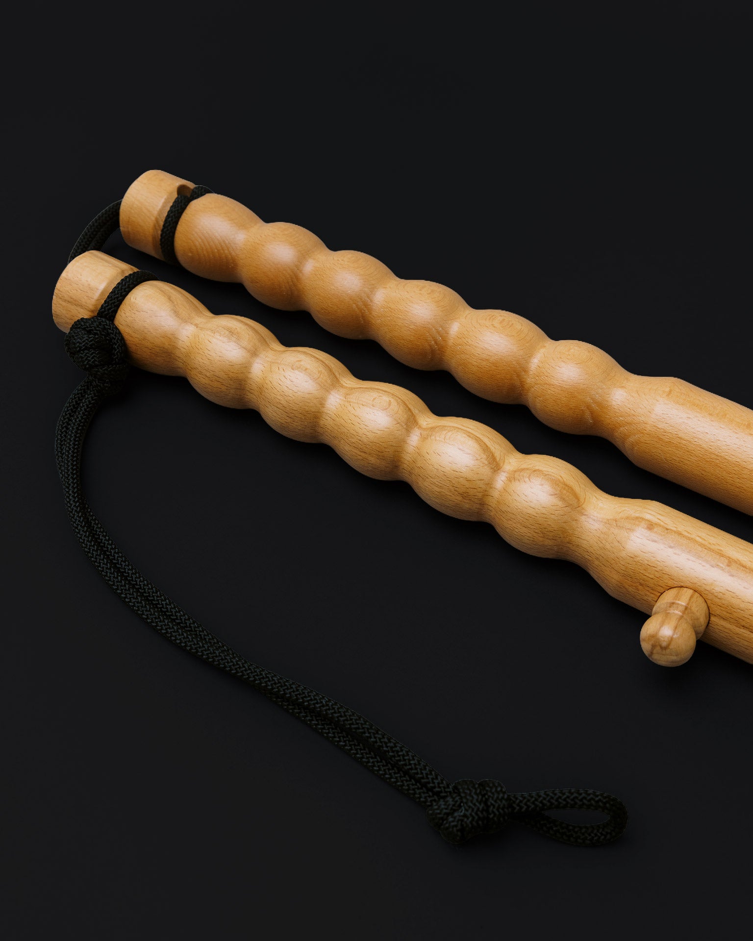 Detail view of wooden massage sticks and chord on black mat