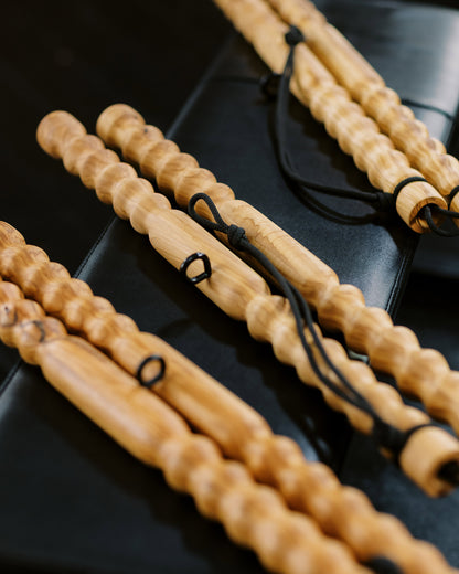 Three wooden muscle massage tools laying on a black workout bench
