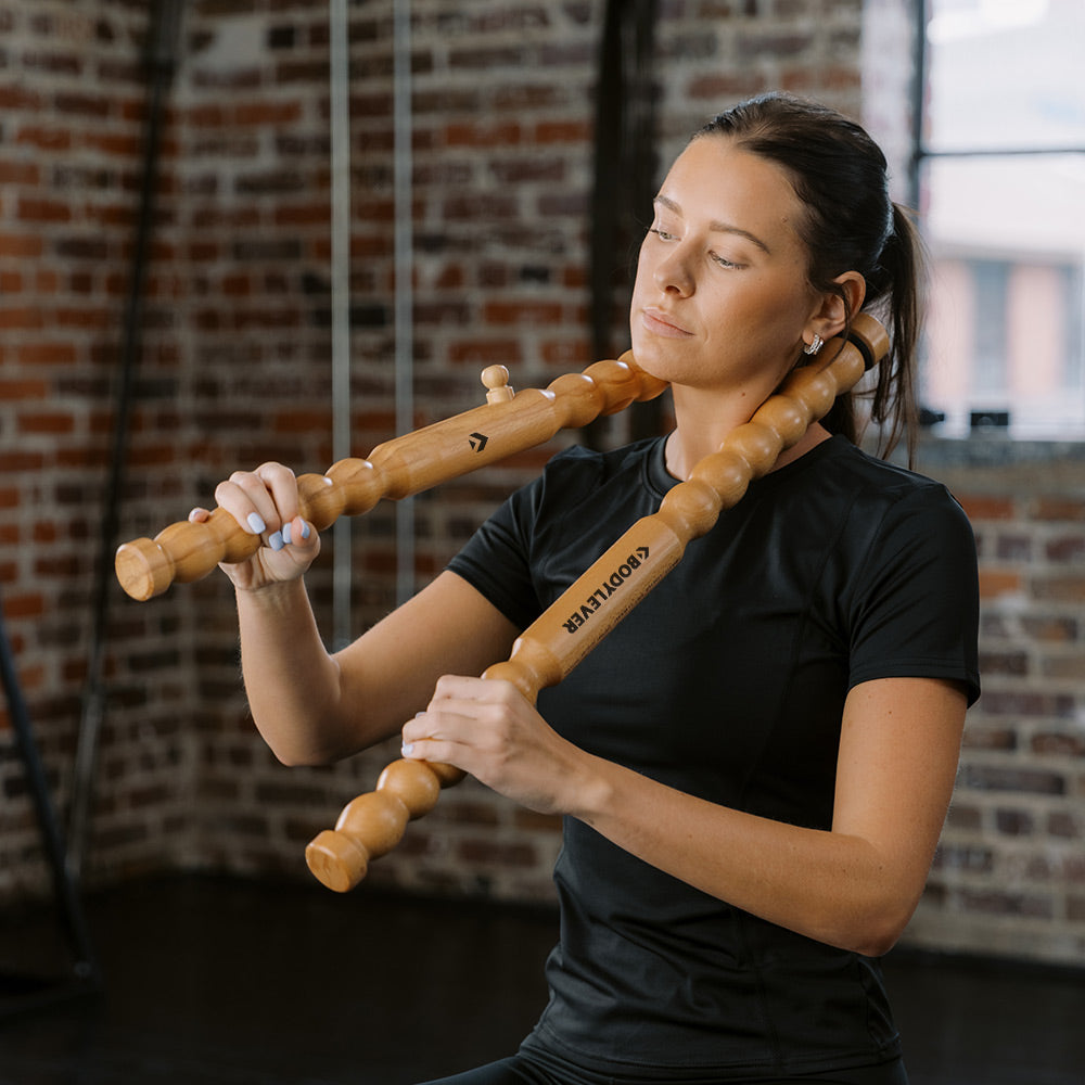 Woman using a wooden BodyLever massage tool on her neck